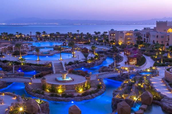 Abendansicht des Kempinski Hotels Soma Bay mit illuminierten Swimmingpools und Blick auf das Meer.
