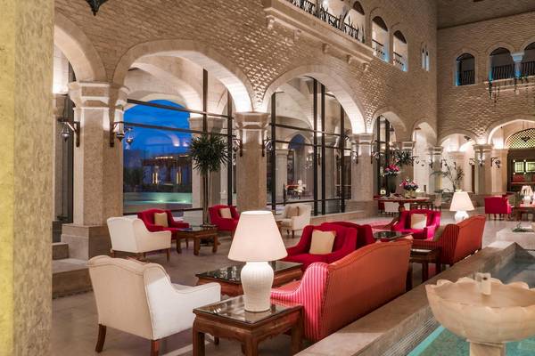 Lobby des Kempinski Hotels Soma Bay mit weißen und roten Möbeln, Lampen und einem Wasserbrunnen.