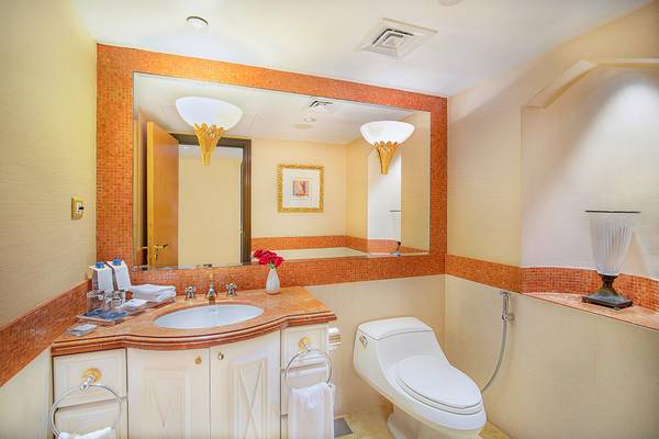 Badezimmer im Sheraton Abu Dhabi Hotel mit Spiegel, Waschbecken, Toilette und Dekoration.