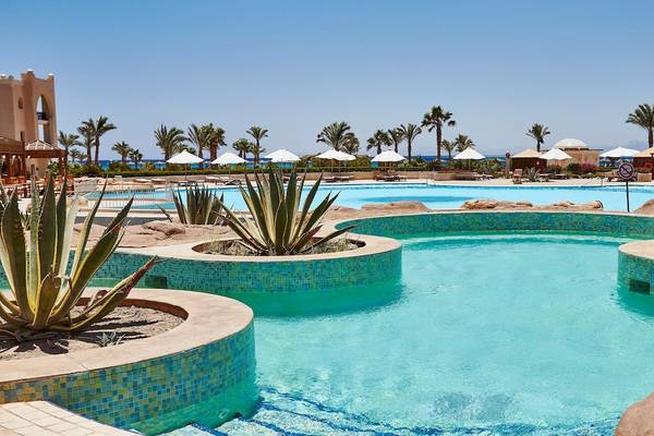 Außenpool des Kempinski Hotels Soma Bay mit mehreren Pflanzen und weißen Sonnenschirmen.