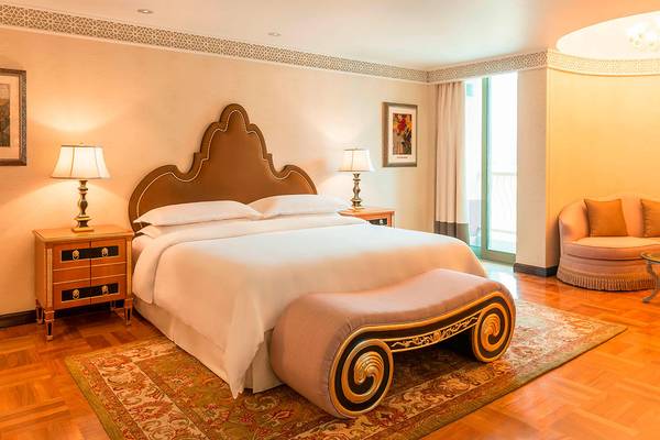 Luxuriöses Schlafzimmer im Sheraton Abu Dhabi Hotel mit einem großen Bett, Nachttischen, Lampen und einem eleganten Kopfteil.