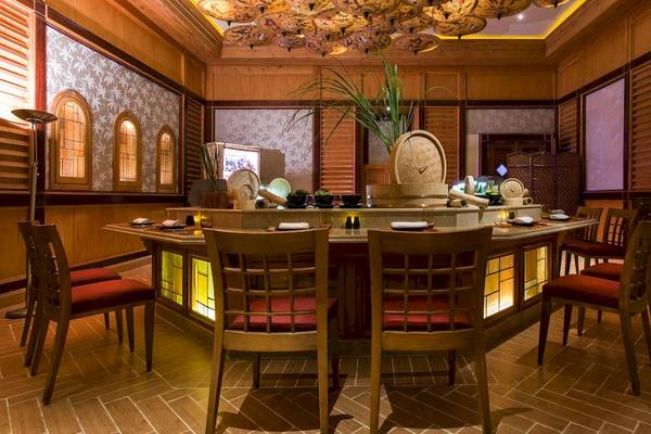 Innenbereich des Kempinski Hotel Soma Bay mit einem Tisch und Stühlen, umgeben von Holzelementen und beleuchteten Wänden.