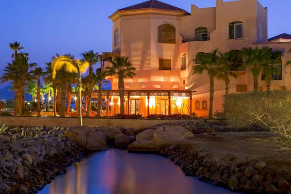 Das Kempinski Hotel Soma Bay ist bei Nacht mit warmem Licht beleuchtet, umgeben von Palmen und Felsen.