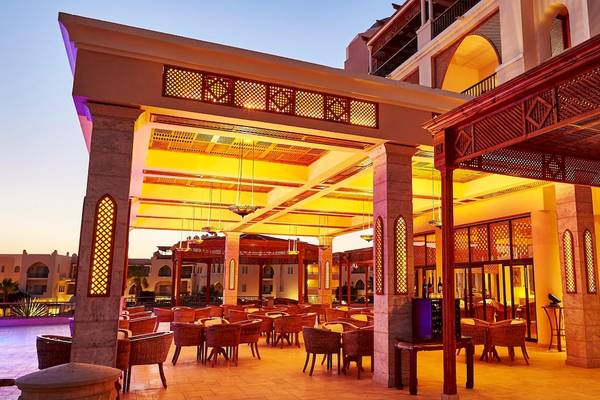 Außenbereich des Kempinski Hotel Soma Bay mit abendlicher Beleuchtung und rustikalen Möbeln.