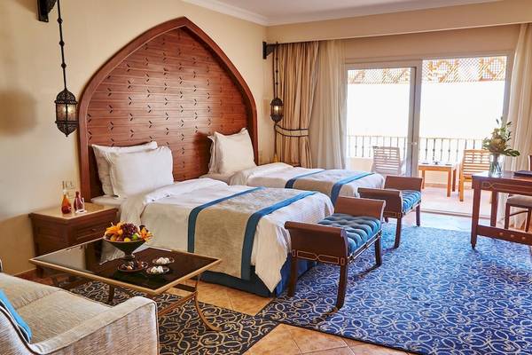 Suite-Zimmer im Kempinski Hotel Soma Bay mit zwei Betten, einem Wohnzimmerbereich und einem Balkon.