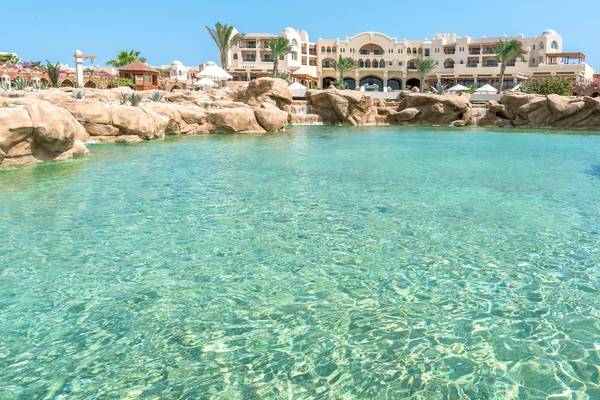 Ein kristallklarer Pool im Kempinski Hotel Soma Bay, umgeben von Felsen und Wasserfällen.