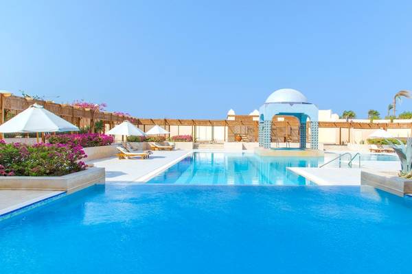 Ein Swimmingpool im Kempinski Hotel Soma Bay mit Sonnenliegen und Sonnenschirmen.