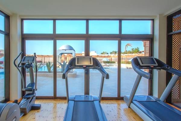 Fitnessraum im Kempinski Hotel Soma Bay mit Blick auf den Pool und das Außengelände.