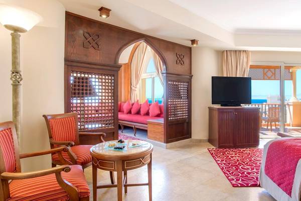 Zimmer im Kempinski Hotel Soma Bay mit Balkon, Fernseher, Sofa und Meerblick.