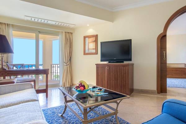 Hotelzimmer im Kempinski Hotel Soma Bay mit Fernseher, Tisch, Sessel und Aussicht.