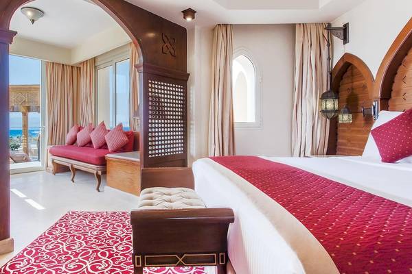 Innenansicht der Suite im Kempinski Hotel Soma Bay mit einem großen Bett, einem roten Teppich und einem Fenster mit Meerblick.