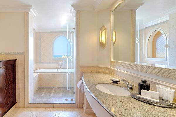 Badezimmer im Kempinski Hotel Soma Bay mit Badewanne, Dusche, Waschbecken und Spiegel.