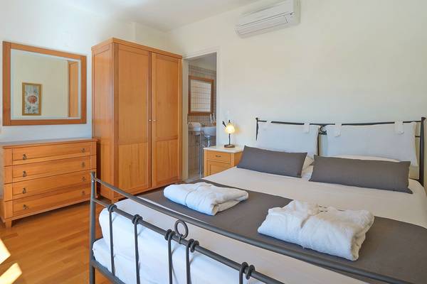 Schlafzimmer im Miramare Resort & Spa mit Bett, Nachttisch, Lampe, Schrank und Spiegel.