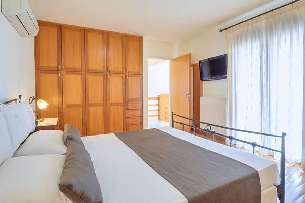 Doppelbett im Zimmer im Miramare Resort & Spa mit weißem Laken, grauer Decke und Holzschränken.