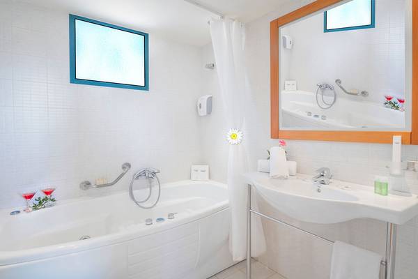 Badezimmer im Miramare Resort & Spa mit Badewanne, Waschbecken und Spiegel.
