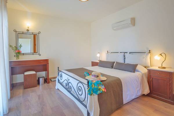 Schlafzimmer im Miramare Resort & Spa mit einem Bett, Nachttischen und einem Spiegel.