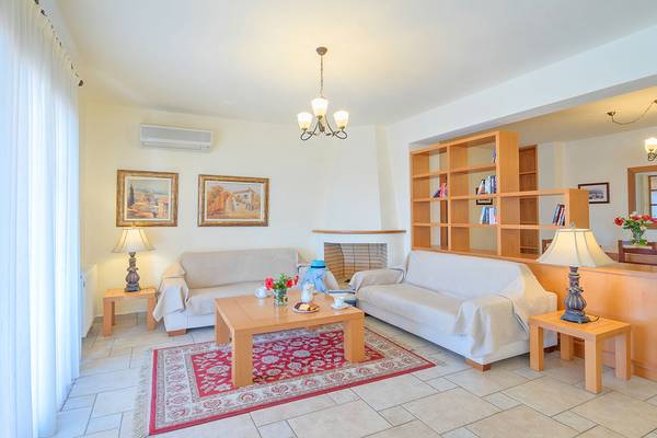 Wohnzimmer im Miramare Resort & Spa mit zwei Sofas, Tisch, Teppich, Lampen und Bücherregal.