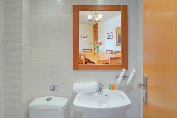 Ein Badezimmer mit einem Spiegel, Toilette und Waschbecken, das einen Blick in ein Esszimmer bietet.