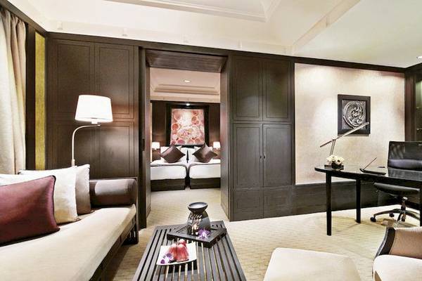 Innenansicht der Suite im Banyan Tree Bangkok mit Wohnzimmer, Schreibtisch und Schlafzimmerbereich.