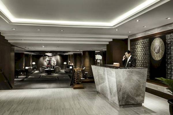 Empfangsbereich im Banyan Tree Bangkok mit Marmortheke und Angestelltem am Telefon