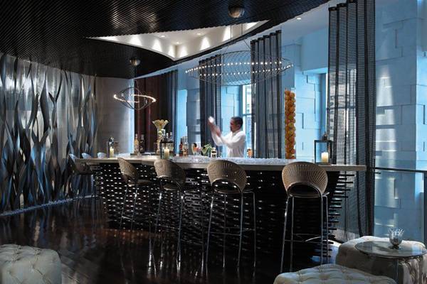 Hotellounge-Bar mit Barkeeper, der einen Cocktail mixt, während Gäste an der Bar sitzen.