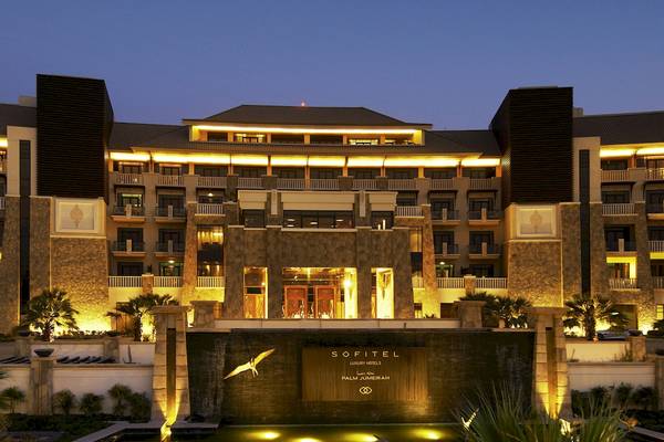 Nachtansicht des Sofitel Dubai The Palm Hotels mit beleuchteter Fassade und Wasserfall
