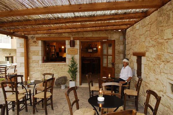 Außenbereich des Cactus Royal Hotels mit einer Terrasse, Holzmöbeln, Tischen, Stühlen und einem sitzenden Mann.