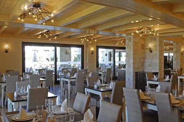 Innenansicht des Restaurants im Cactus Royal Hotel mit vielen Tischen und Stühlen, Holzbalken und Kronleuchtern.