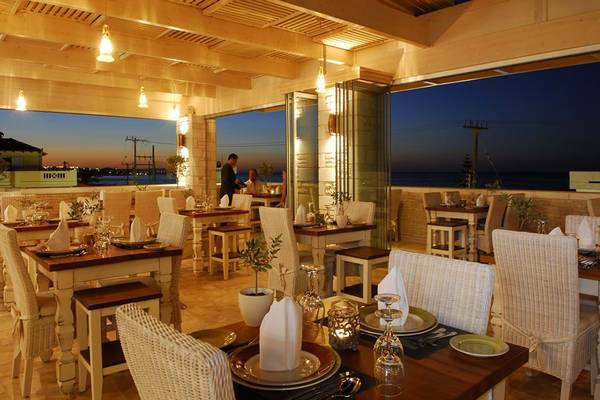 Innenansicht des Cactus Royal Restaurants bei Abend mit Blick auf das Meer und mehrere gedeckte Tische.