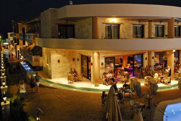 Foto des Cactus Royal Hotels bei Nacht mit Außenbereich und Pool, viele Gäste sitzen draußen.