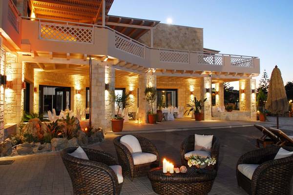 Außenbereich des Cactus Royal Hotels bei Nacht mit illuminiertem Gebäude, Stühle und Tische auf der Terrasse