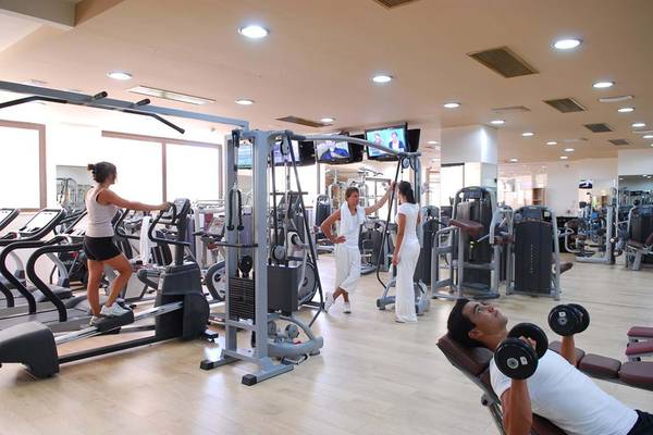 Fitnessstudio im Hotel Cactus Royal mit verschiedenen Geräten und Personen beim Training.