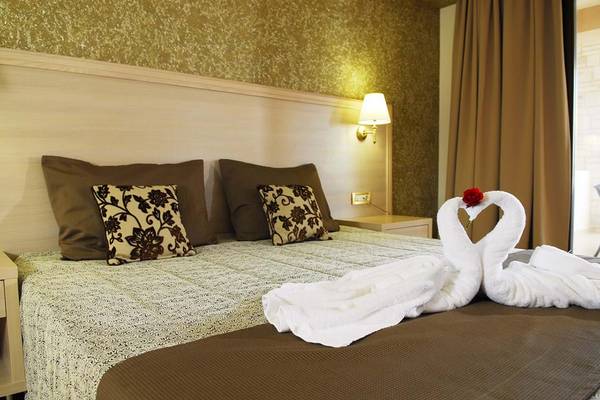 Bett im Cactus Royal Hotel mit zwei weißen Handtüchern, die in Form eines Schwans gefaltet sind.