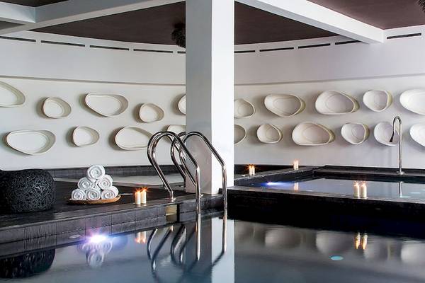 Spa-Bereich im Myconian Utopia Resort mit Innenpool, Kerzen und weißen Wänden.