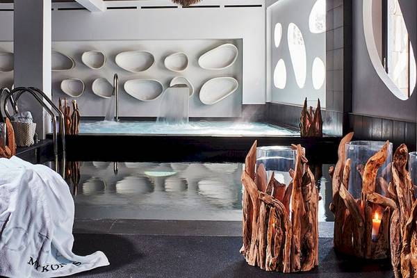 Innenansicht des Spa-Bereichs im Myconian Utopia Resort mit Jacuzzi, weißen Wandverkleidungen und schwarzen Möbeln.