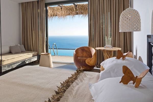 Luxus Schlafzimmer mit Meerblick im Myconian Utopia Resort, inklusive Bett, Sofa, Tisch und Fernseher.