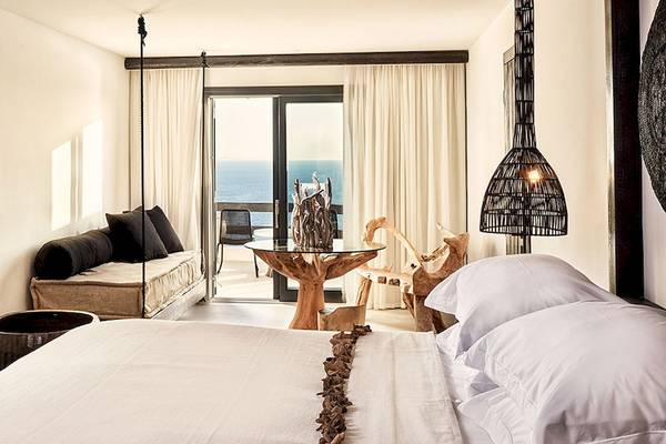 Innenansicht eines Schlafzimmers im Myconian Utopia Resort mit Meerblick, Holzmöbeln und einem Bett.