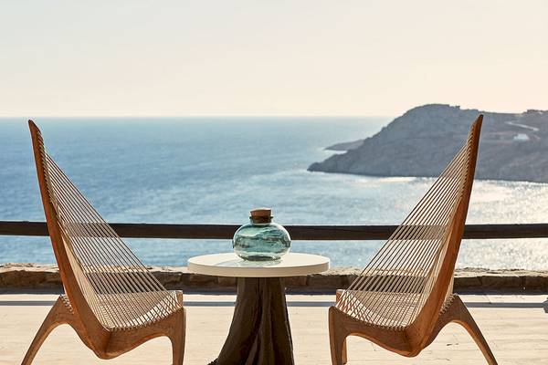 Aussicht auf das Meer vom Myconian Utopia Resort mit zwei Holzstühlen und einem kleinen Tisch.