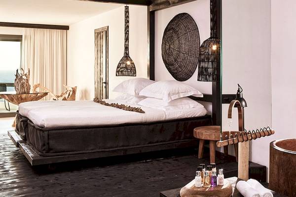 Schlafzimmer im Myconian Utopia Resort mit Bett, Lampen, Badewanne und Aussicht auf das Meer.