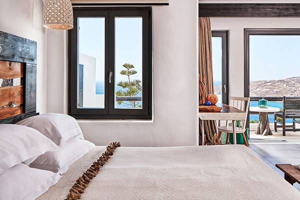 Schlafzimmer im Myconian Utopia Resort mit Meerblick, Fenster, Balkon, Tisch, Stühle und Lampen.