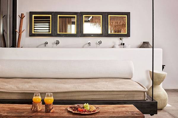Innenansicht des Myconian Utopia Resorts mit Bett, Lampen und Tisch.