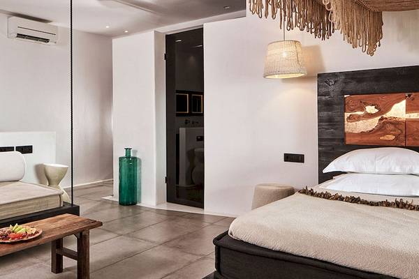 Innenansicht des Myconian Utopia Resorts mit Bett, Couch, Tisch und Dekorationen