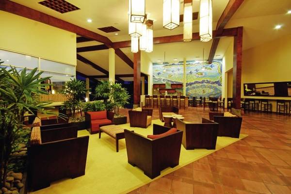 Lobbybereich des Fiesta Resort All Inclusive mit Möbeln, Pflanzen und einer großen Wandmalerei.