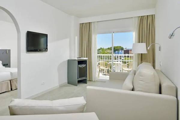 Ein modernes Hotelzimmer mit zwei Betten, einem Fernseher, einem Sofa und einer Terrasse.