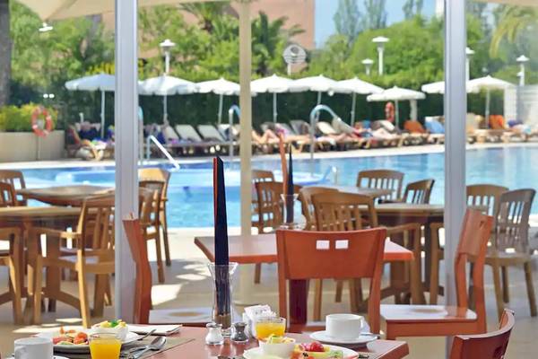 Poolseite des Sol Guadalupe Hotels mit Restaurant, Tischen, Stühlen und Sonnenschirmen.