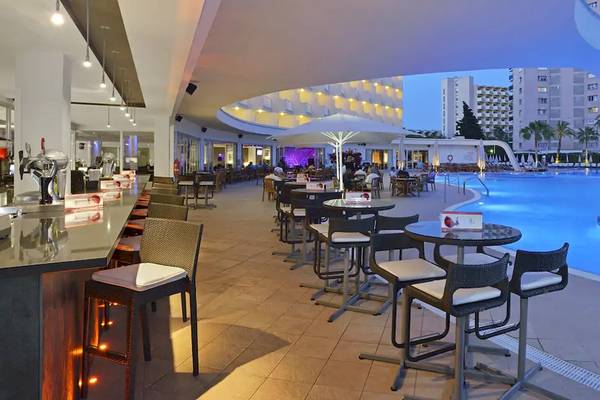 Pool-Lounge im Sol Guadalupe Hotel mit Tischen, Stühlen und beleuchtetem Pool