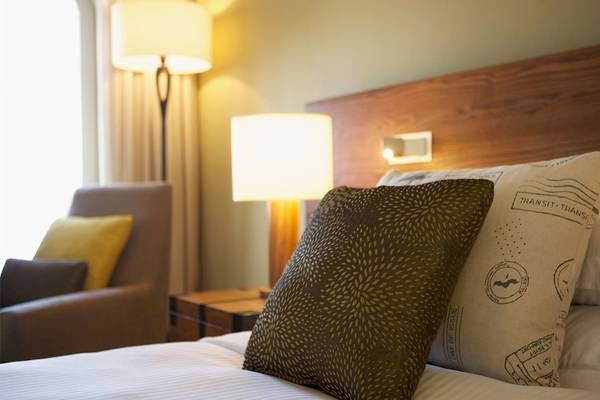 Bett im Outrigger Mauritius Beach Resort mit Kissen und Lampen neben einem Fenster.