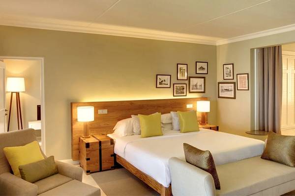 Hotelzimmer im Outrigger Mauritius Beach Resort mit Bett, Sesseln und Dekor.