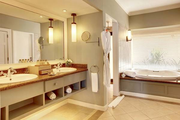 Badezimmer im Outrigger Mauritius Beach Resort mit Badewanne, Waschbecken und Spiegel.