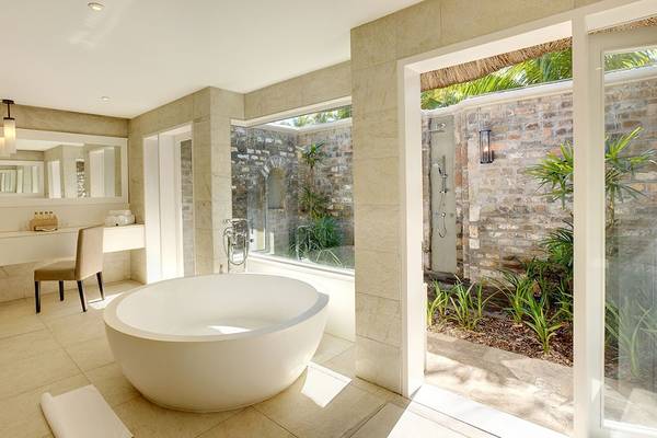 Badezimmer im Outrigger Mauritius Beach Resort mit Badewanne und Außendusche.